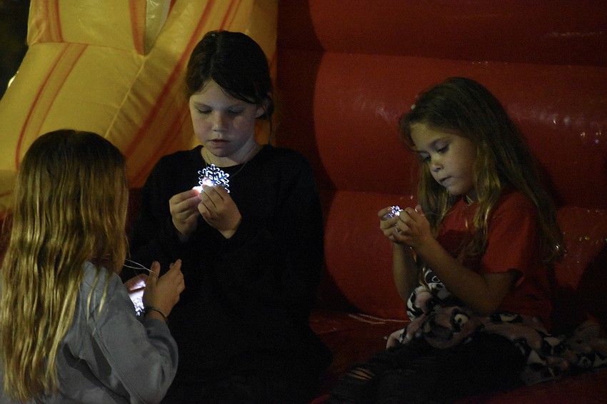Sagan Shinn, 8, Charis Hogue, 9, and Isla Shinn, 6, look at the snowflake necklaces given out to attendees.