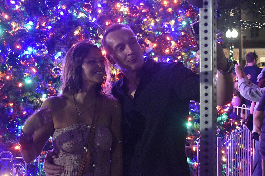 Emilie Campos and Slawek Kaszubowski take a selfie in front of the tree.