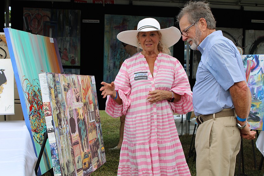 Marie Therese Lacroix shares insights into her artwork with viewer John Davis at the Lawn Party.