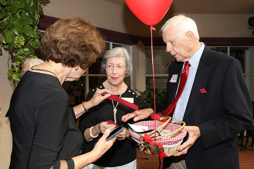 Barbara Chertok purchases raffle tickets from Antonette Cunningham and Bernie Bartek.