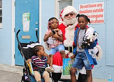 Santa Claus welcomes Ketia Alennsia Joachim, Henry Lerricia Jeanbaptiste and John Kerry Jeanbaptiste for a morning of family holiday fun at Stillpoint Mission. Longboat Island Chapel and other local groups helped make the Dec. 6 toy distribution happen.