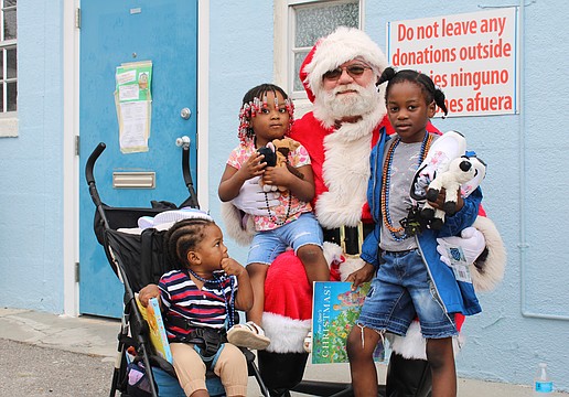 Santa Claus welcomes Ketia Alennsia Joachim, Henry Lerricia Jeanbaptiste and John Kerry Jeanbaptiste for a morning of family holiday fun at Stillpoint Mission. Longboat Island Chapel and other local groups helped make the Dec. 6 toy distribution happen.