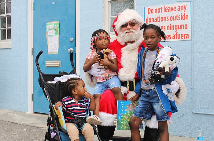 Santa Claus welcomes Ketia Alennsia Joachim, Henry Lerricia Jeanbaptiste and John Kerry Jeanbaptiste for a morning of family holiday fun at Stillpoint Mission. Longboat Island Chapel and other local groups helped make the Dec. 6 toy distribution happen.