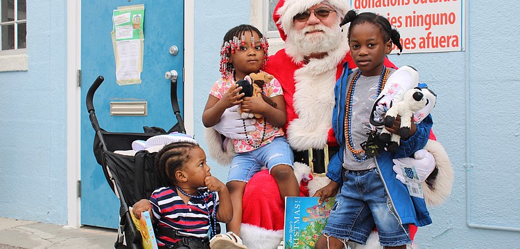 Santa Claus welcomes Ketia Alennsia Joachim, Henry Lerricia Jeanbaptiste and John Kerry Jeanbaptiste for a morning of family holiday fun at Stillpoint Mission. Longboat Island Chapel and other local groups helped make the Dec. 6 toy distribution happen.