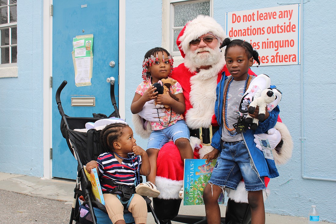 Santa Claus welcomes Ketia Alennsia Joachim, Henry Lerricia Jeanbaptiste and John Kerry Jeanbaptiste for a morning of family holiday fun at Stillpoint Mission. Longboat Island Chapel and other local groups helped make the Dec. 6 toy distribution happen.