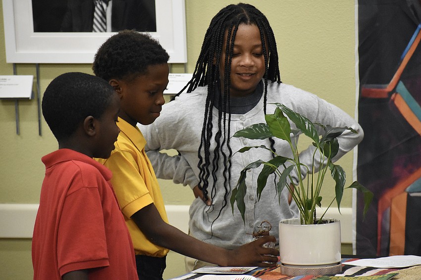 Jabari Simon, 7, Makhi Mann, 8, and Makyla Williams, 8, students at Exceptional Tutoring, work together to water a plant during the ceremony.