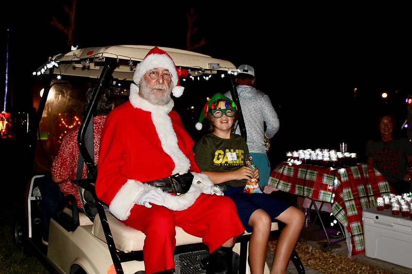 Santa Claus, accompanied by Callen Finnigan, leads the parade of onlookers judging the entries in the Longboat Harbour Lighting of the Docks.
