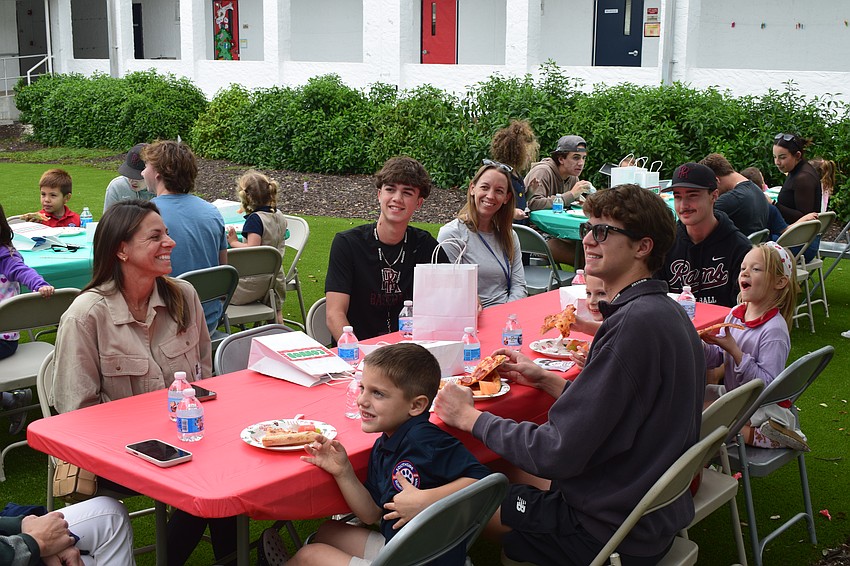 A table of parents, high schoolers and kindergartners smile for photos during their Dec. 9 pizza party at Southside Elementary School. The number of mentors in Riverview Readers has more than doubled over the last four years.