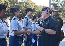 Braden River High School junior Mystique Quinones shakes hands with Dave Daily, post commander for VFW Post 12055, as she receives her $100 reward for her essay which answered the question “How are you showing patriotism and support for our country?”