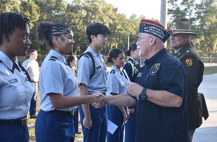 Braden River High School junior Mystique Quinones shakes hands with Dave Daily, post commander for VFW Post 12055, as she receives her $100 reward for her essay which answered the question “How are you showing patriotism and support for our country?”