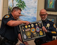 Longboat Key Police Deputy Chief Frank Rubino (left) accepts a framed display of medals, patches and pins that demonstrate his 45-year career in law enforcement.