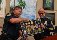 Longboat Key Police Deputy Chief Frank Rubino (left) accepts a framed display of medals, patches and pins that demonstrate his 45-year career in law enforcement.