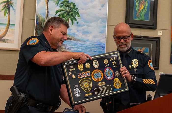 Longboat Key Police Deputy Chief Frank Rubino (left) accepts a framed display of medals, patches and pins that demonstrate his 45-year career in law enforcement.