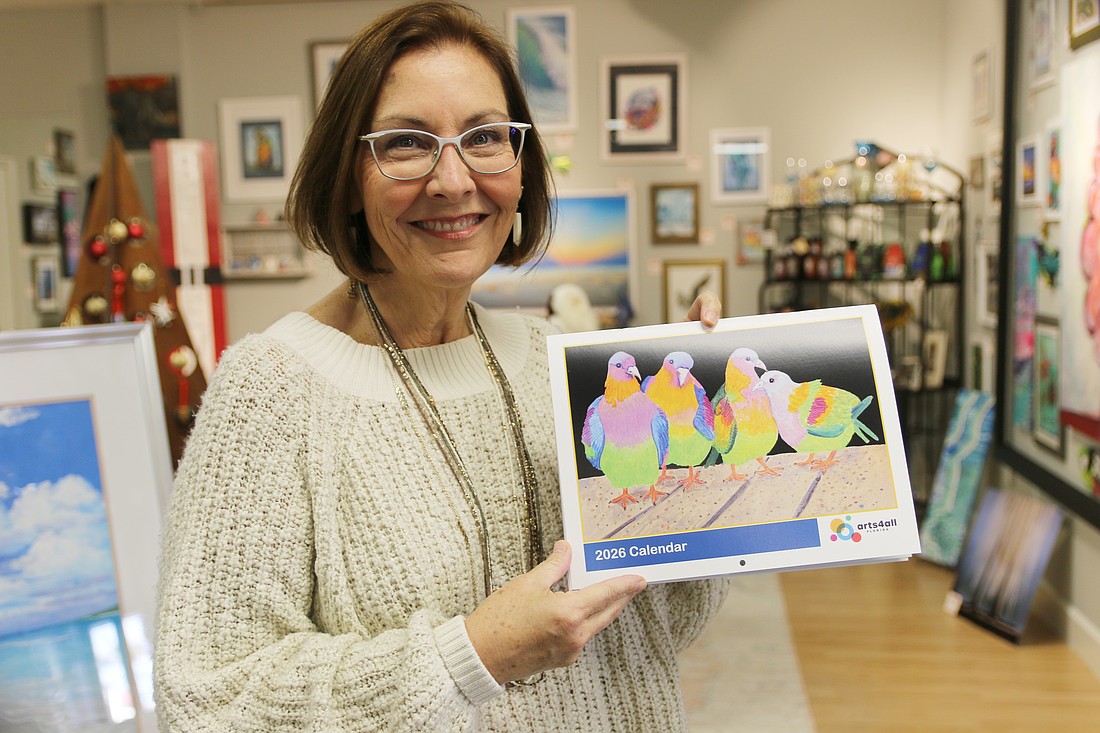 Sara Meinking holds up an Arts4All calendar, featuring an art piece on the cover by Margaret Zabor, titled "Uncommon Pigeons." Photo by Jarleene Almenas