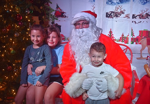 Capri Finan, 7, Madelyn Finan, 9 and Maverick Finan, 3, pose with Santa after telling him what they want for Christmas, which includes a doll house and a trampoline.