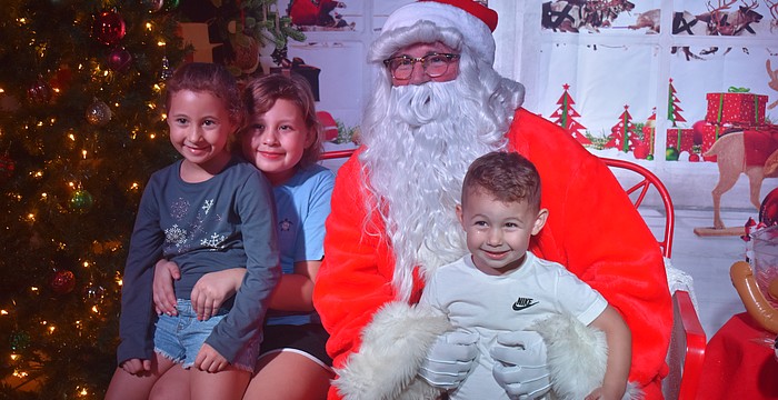 Capri Finan, 7, Madelyn Finan, 9 and Maverick Finan, 3, pose with Santa after telling him what they want for Christmas, which includes a doll house and a trampoline.