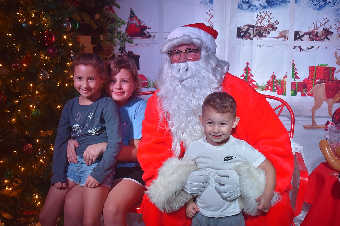 Capri Finan, 7, Madelyn Finan, 9 and Maverick Finan, 3, pose with Santa after telling him what they want for Christmas, which includes a doll house and a trampoline.