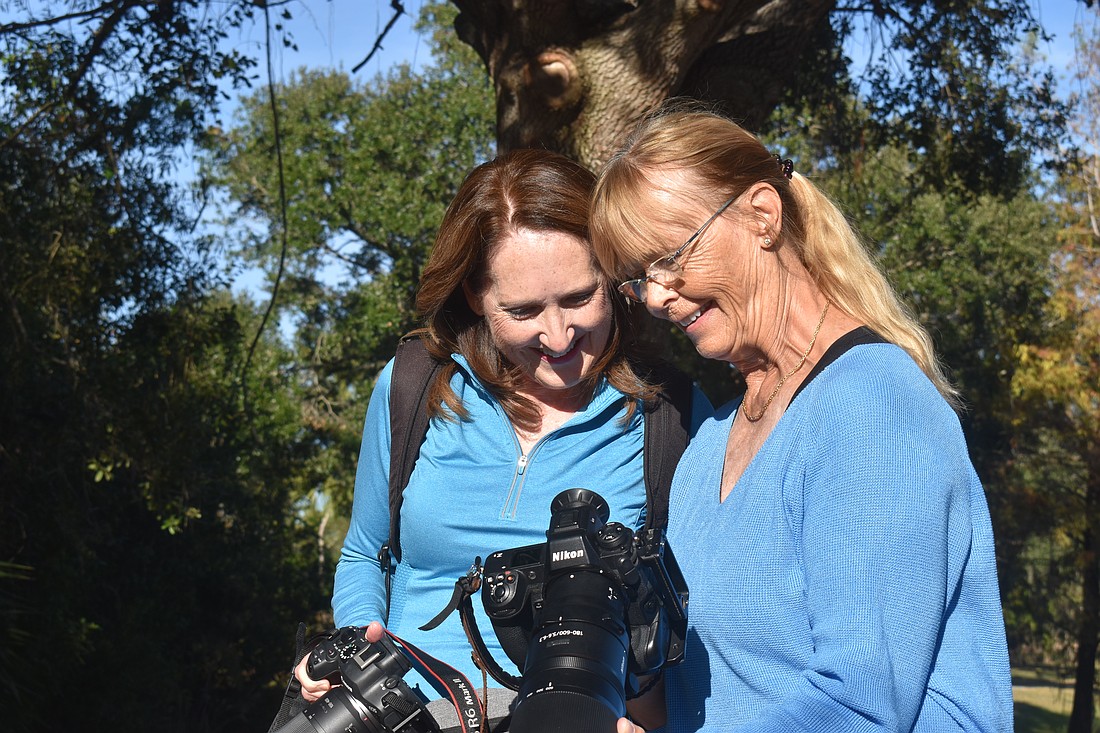 Lynnette Beecher and Gunilla Imshaug, members of the Lakewood Ranch Digital Photography Club, check out a photo of a baby alligator that was taken moments before.