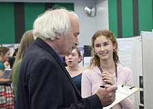 Nicholas Savarese, a teacher who has a background in chemical engineering, judges junior Lillian Pevzner-Downer's project on the comparison of conventionally grown crops with chemicals and pesticides versus organically grown crops at the Lakewood Ranch High School Science Fair.