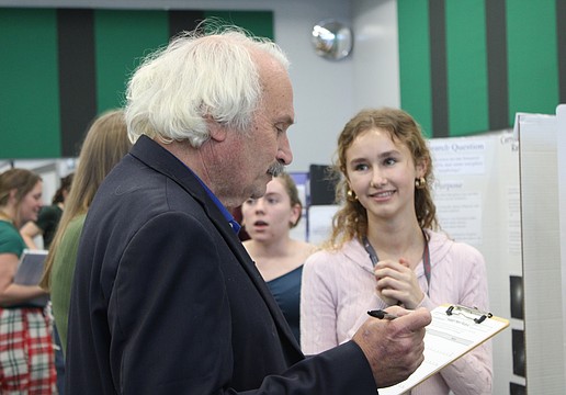 Nicholas Savarese, a teacher who has a background in chemical engineering, judges junior Lillian Pevzner-Downer's project on the comparison of conventionally grown crops with chemicals and pesticides versus organically grown crops at the Lakewood Ranch High School Science Fair.