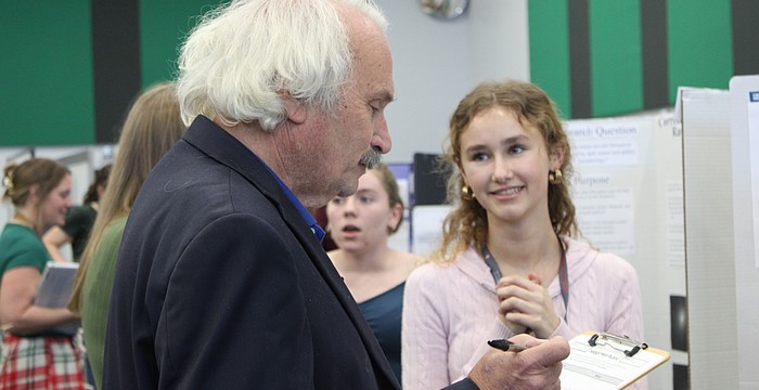 Nicholas Savarese, a teacher who has a background in chemical engineering, judges junior Lillian Pevzner-Downer's project on the comparison of conventionally grown crops with chemicals and pesticides versus organically grown crops at the Lakewood Ranch High School Science Fair.