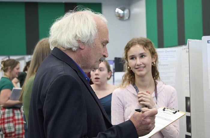 Nicholas Savarese, a teacher who has a background in chemical engineering, judges junior Lillian Pevzner-Downer's project on the comparison of conventionally grown crops with chemicals and pesticides versus organically grown crops at the Lakewood Ranch High School Science Fair.