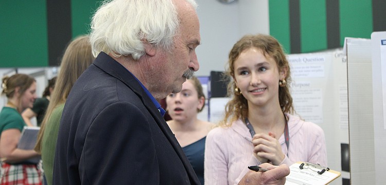 Nicholas Savarese, a teacher who has a background in chemical engineering, judges junior Lillian Pevzner-Downer's project on the comparison of conventionally grown crops with chemicals and pesticides versus organically grown crops at the Lakewood Ranch High School Science Fair.