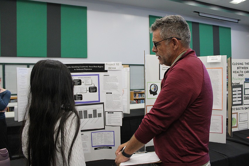 Tas Zahin, a sophomore, receives advice on her project from Jeff Camp, a science teacher and judge. He recommends all students practice their presentation to whoever will listen.