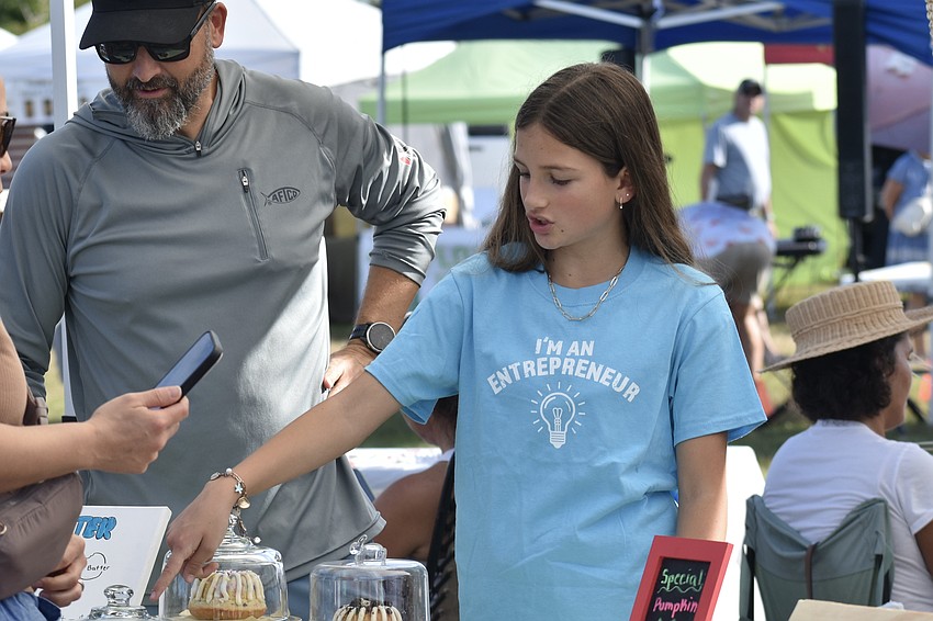 Jeremy Taylor stands beside his daughter Hannah Taylor, 13, as she speaks with a customer about her bundt cakes she makes herself.