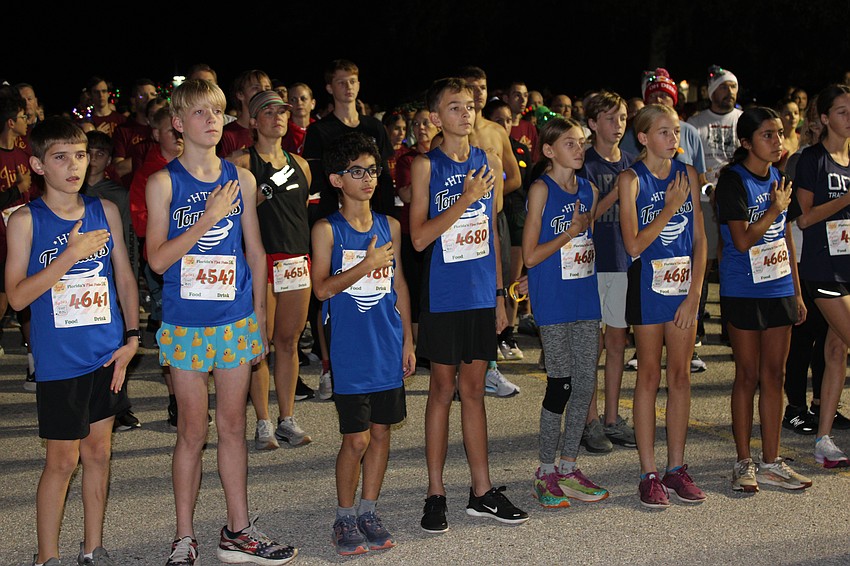 Members of Brandon's Fishhawk Roadrunners Club show their respect during the National Anthem at the Jingle 5K.