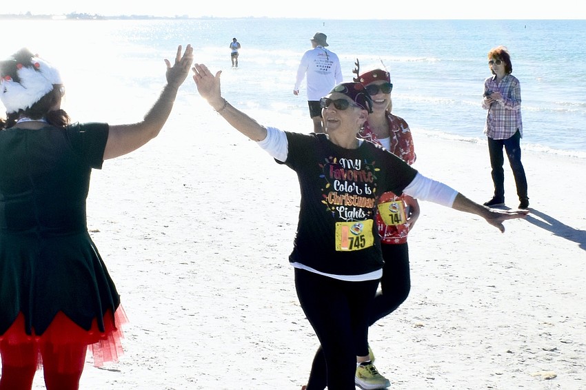 A Sarasota County employee offers a hand slap to Jackie Peek and Nikole Peek as they near the finish line.