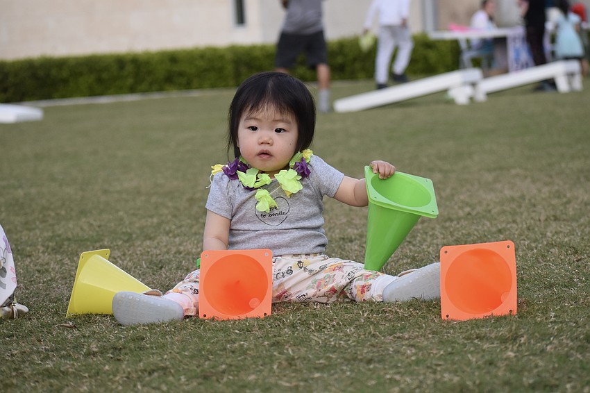 Hailey Zhang, 1, plays with cones in the park grass.