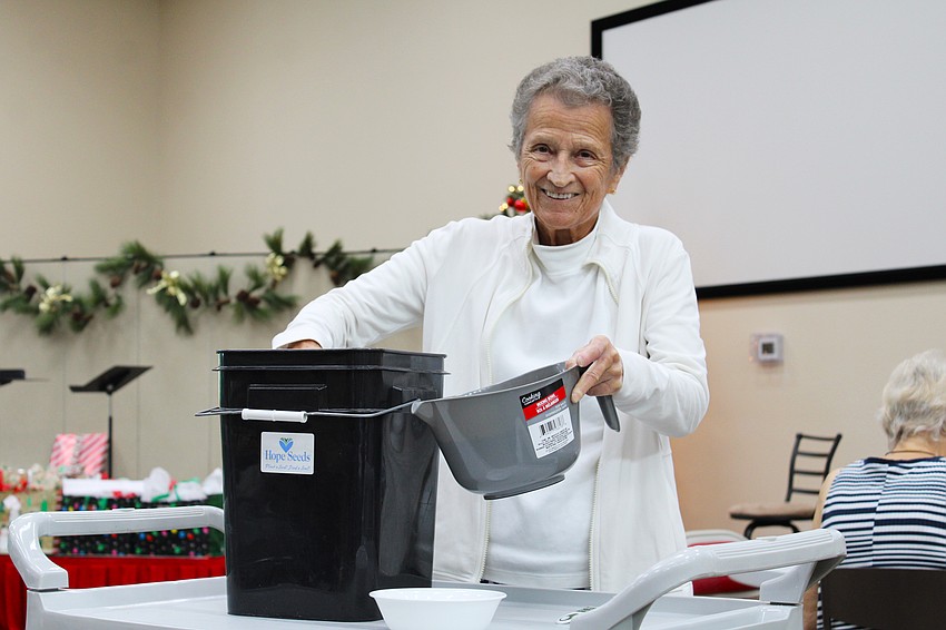Sue Wertman refills a pitcher with loose coriander seeds for volunteers with Hope Seeds to pack into 1 teaspoon sachets.