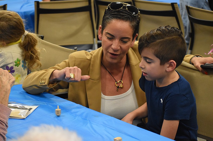 Inbal August and her son Yanai August, 7, spin a dreidel. Inbal August and her son Yanai August, 7, spin a dreidel.