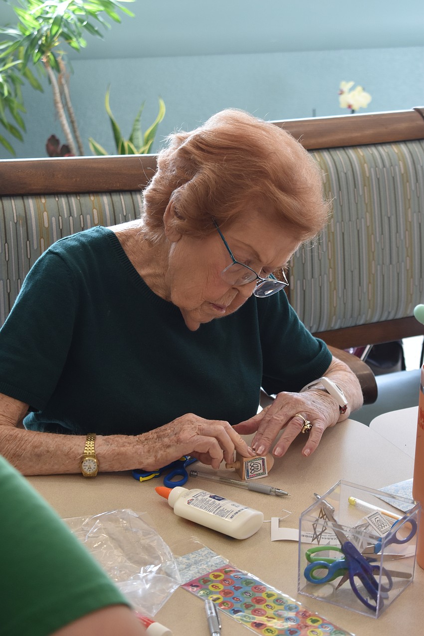 Sandy Klein attaches designs to a dreidel. Sandy Klein attaches designs to a dreidel.