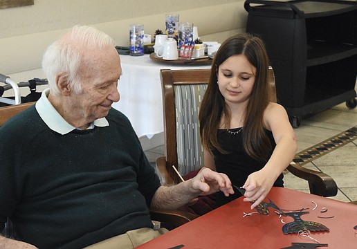 Sixth grader Stella Schechter holds up a finished craft for David Stone.