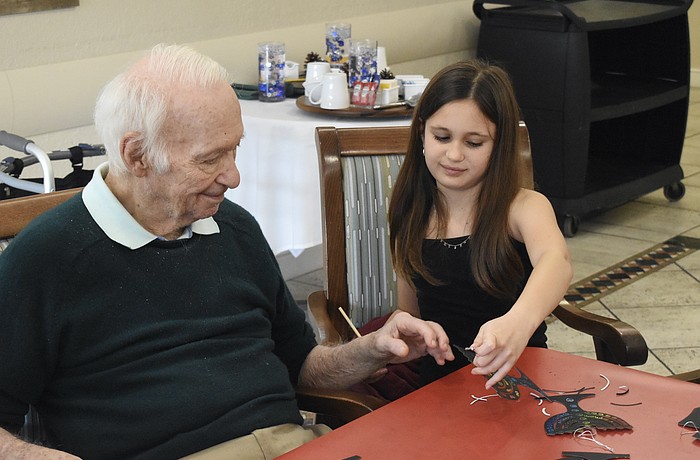 Sixth grader Stella Schechter holds up a finished craft for David Stone.
