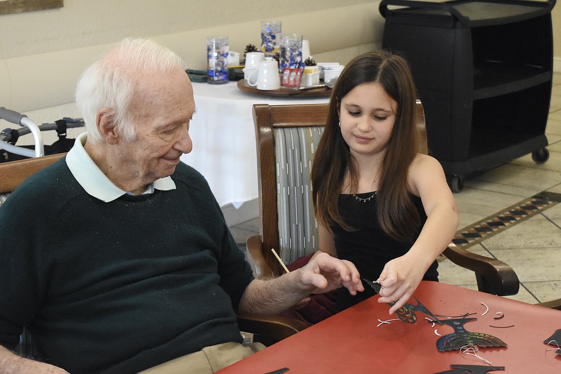 Sixth grader Stella Schechter holds up a finished craft for David Stone.