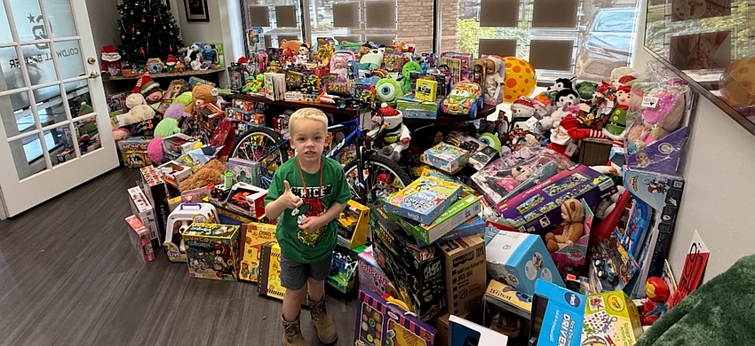 Zander Vinopal stands in front of the hundreds of toys collected for Toys for Tots by Coldwell Banker Realty's collection drive.