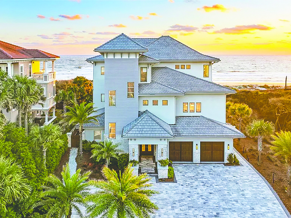Amelia Island oceanfront three-story home features four bedrooms, four full and one half-bathrooms, exercise room, game room, elevator, deck, porch, pool, outdoor kitchen, three-car garage and dune walkover.