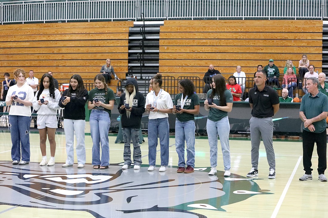 FPC's 2024-25 girls wrestlers are excited to look at their state championship rings. From left: Kendall Bilba, Christina Borgmann, Alexa Calidonio, Alisha Vilar, Joslyn Johnson, Mariah Mills, Juliana Mills, Ana Vilar, coach David Bossardet and assistant coach Steve DeAugustino. Not pictured: Tiana Fries. Photo by Brent Woronoff