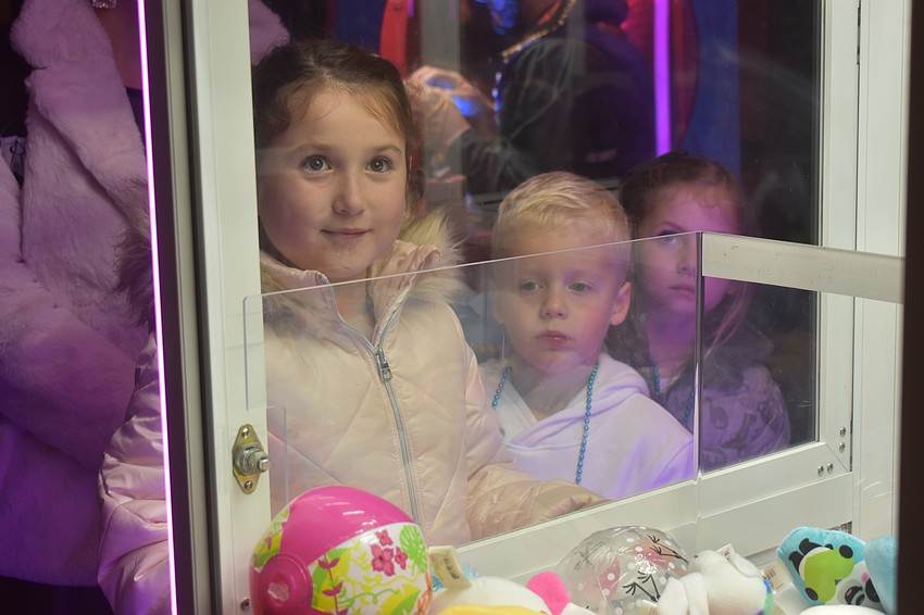Lakewood Ranch's Liliana Kosmalski, 7, returns to the claw machine after winning multiple prizes while Everett Ready, 6, and Juliette Kinsey, 6, wait for their turns.