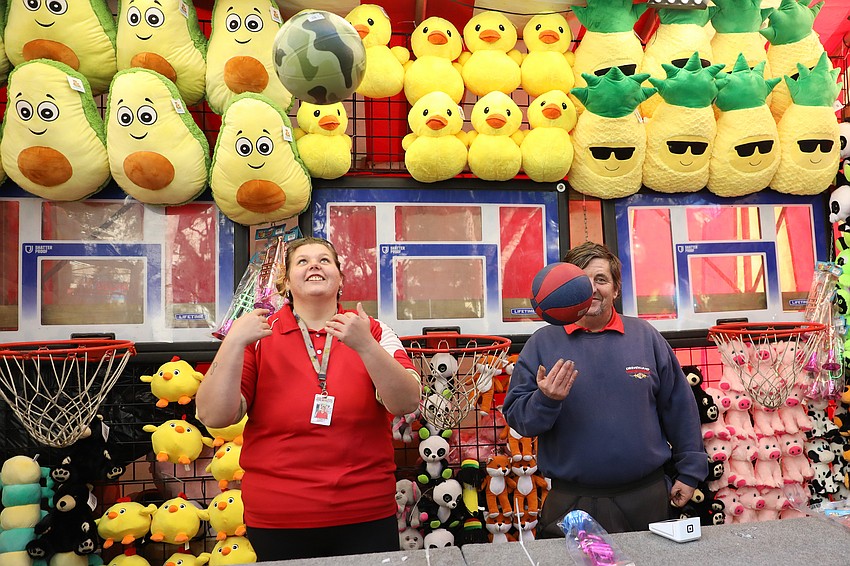 Sierra Varney and David Hughes show customers how easy it is to win stuffed animals by shooting hoops.