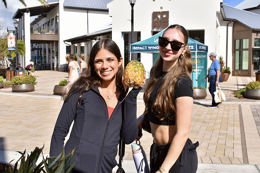 Sarasota's Sofia Gonzalez and Christine Traynor grab a pineapple from the Come Under the Yum Yum Tree stand.