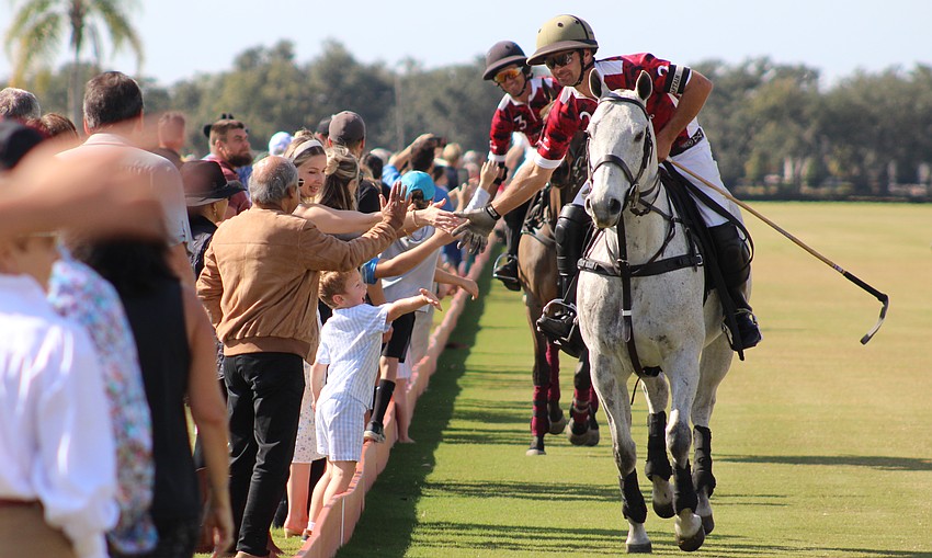 Southside Polo's Mason Wroe and Marcos Onetto (trailing) slap hands with fans before the start of the match Jan. 4 at the Sarasota Polo Club.