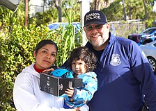 Officer Danny Robbins of the Patrol Division, Community Relations Unit with a recipient of a gift during the Sarasota Police Department's Three Kings Day event.