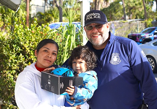 Officer Danny Robbins of the Patrol Division, Community Relations Unit with a recipient of a gift during the Sarasota Police Department's Three Kings Day event.