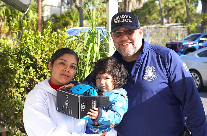 Officer Danny Robbins of the Patrol Division, Community Relations Unit with a recipient of a gift during the Sarasota Police Department's Three Kings Day event.