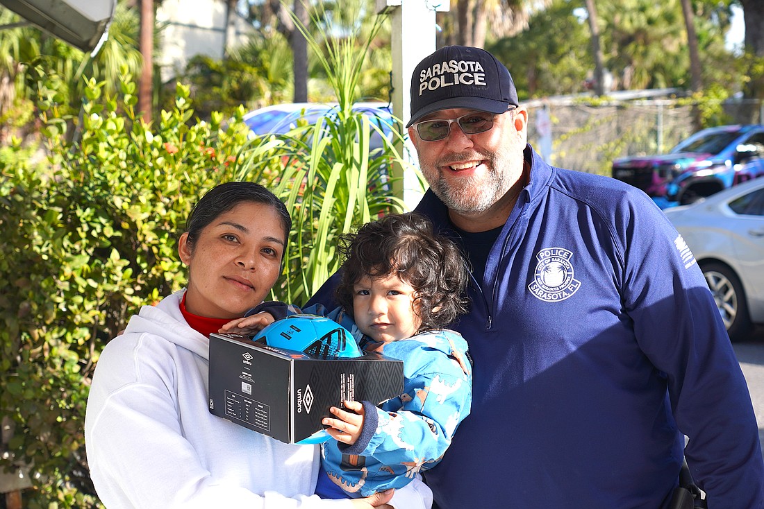 Officer Danny Robbins of the Patrol Division, Community Relations Unit with a recipient of a gift during the Sarasota Police Department's Three Kings Day event.