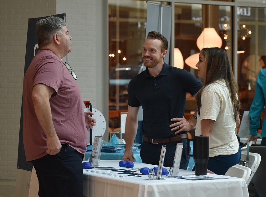 New York's Mark Papagni speaks with doctor of chiropractic Robert Eyerly and chiropractic neurologist Bianca Miret at the Carolina Functional Neurology Center booth.